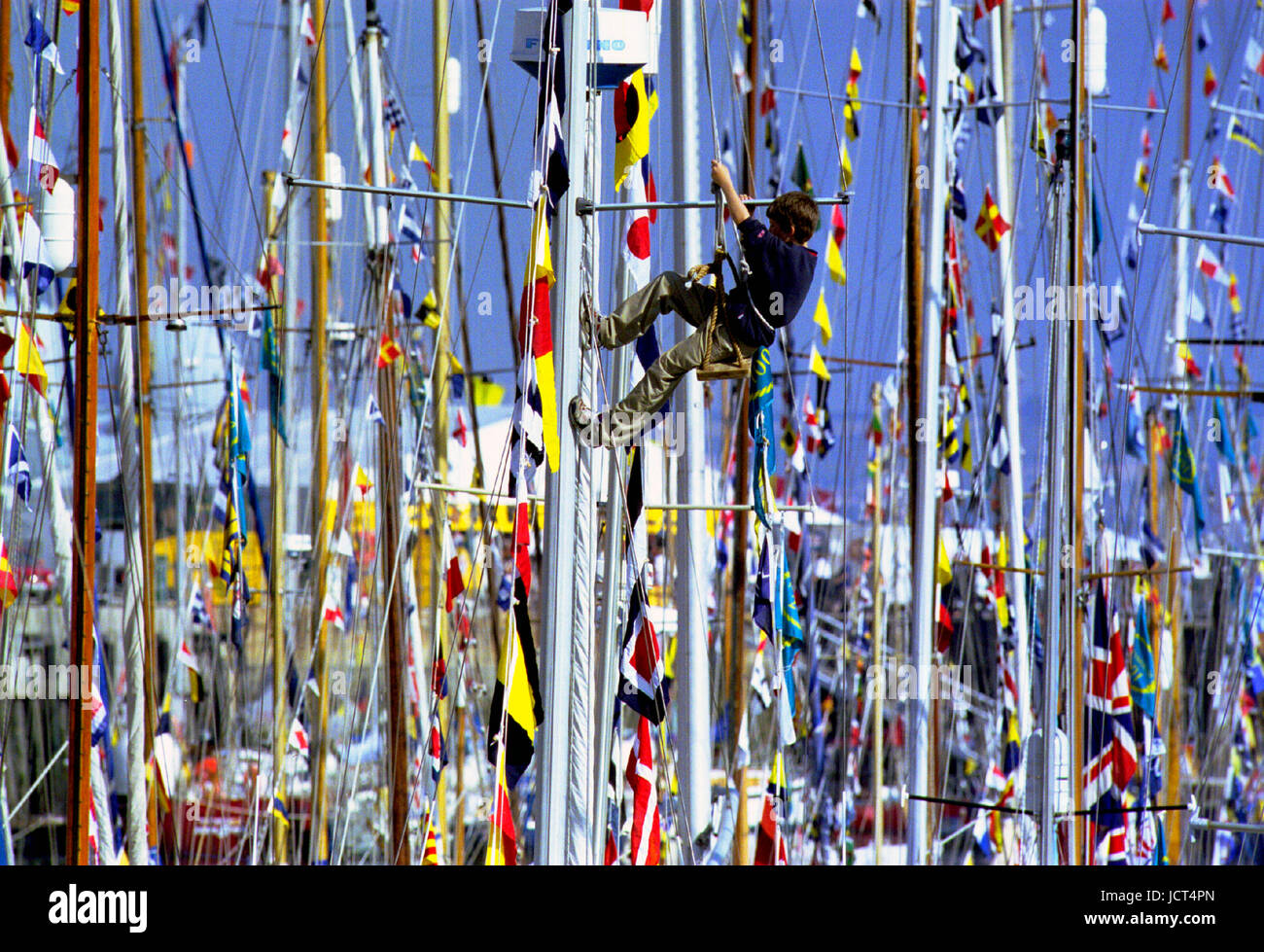 Ein junge Segler in einem Bootsmann Stuhl klettert einen Mast auf dem Festival des Meeres, wenn 1000 Segelschiffe in Portsmouth Naval Dockyard versammelt. Stockfoto