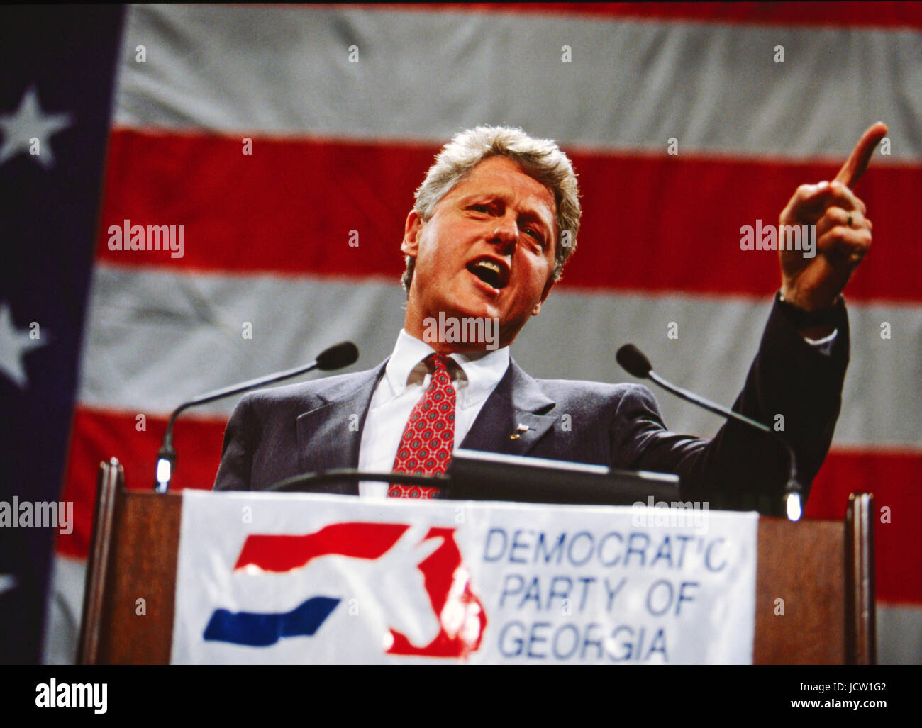 Präsident Bill Clinton spricht vor einer großen amerikanischen Flagge. Stockfoto