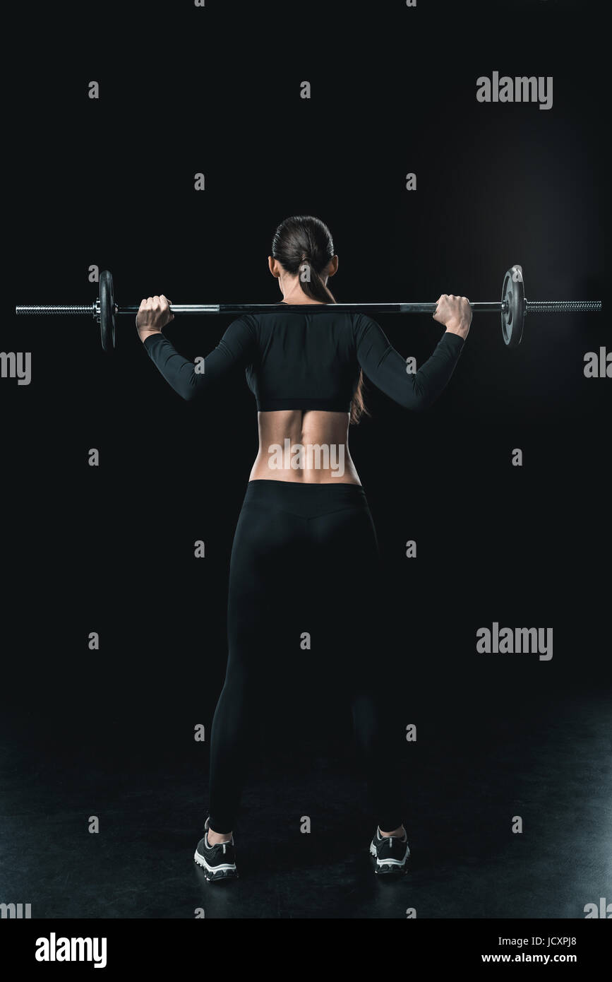 junge Fitness Frau training mit Langhantel isoliert auf schwarz. Stockfoto