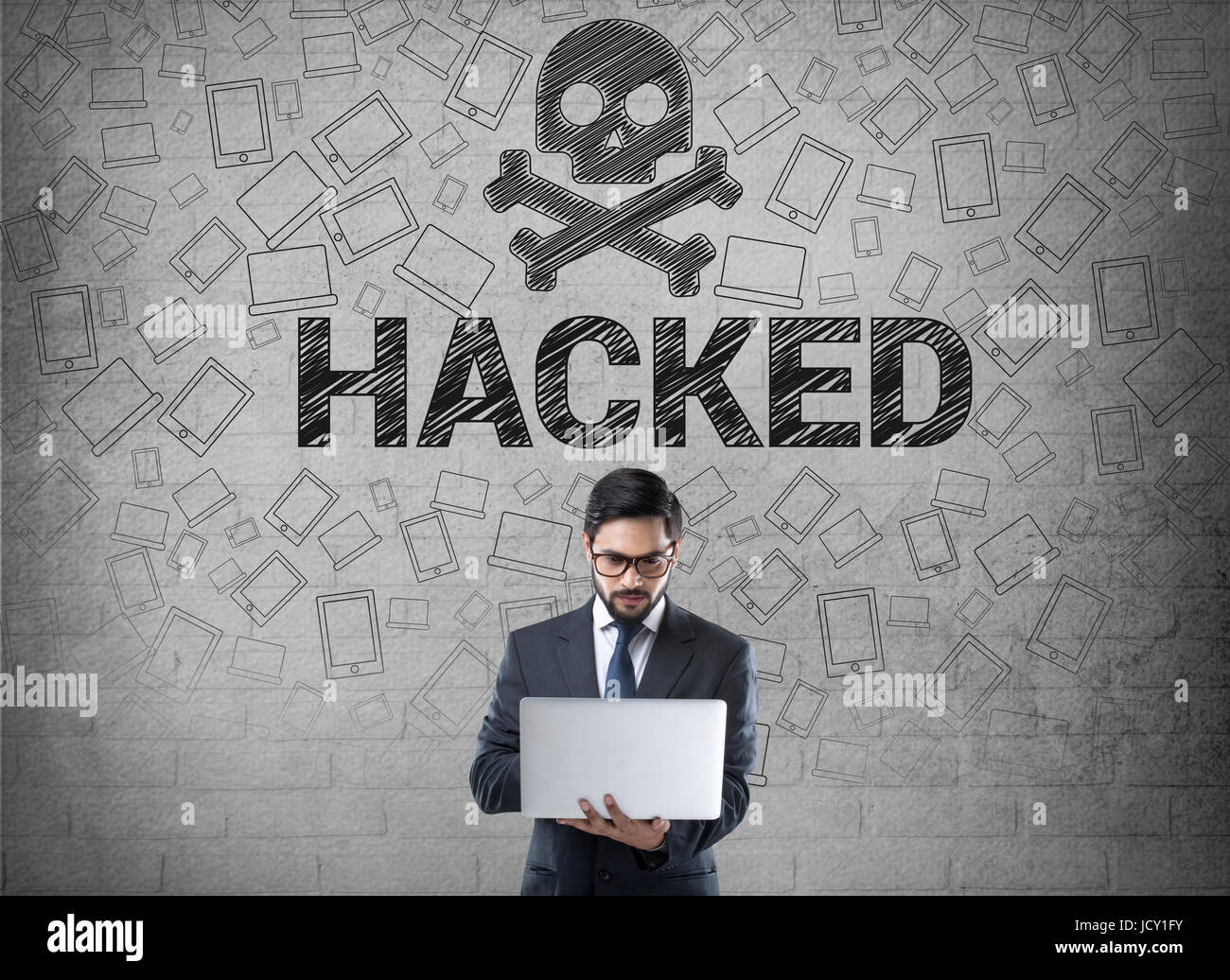 Geschäftsmann mit Laptop vor Wand mit Totenkopf-Symbol, gehackten Computer-Konzept Stockfoto