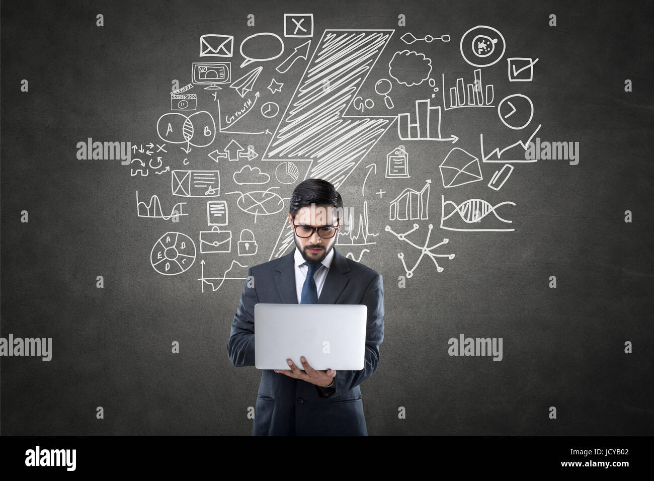 Geschäftsmann mit Laptop vor Tafel mit Ikonen Stockfoto