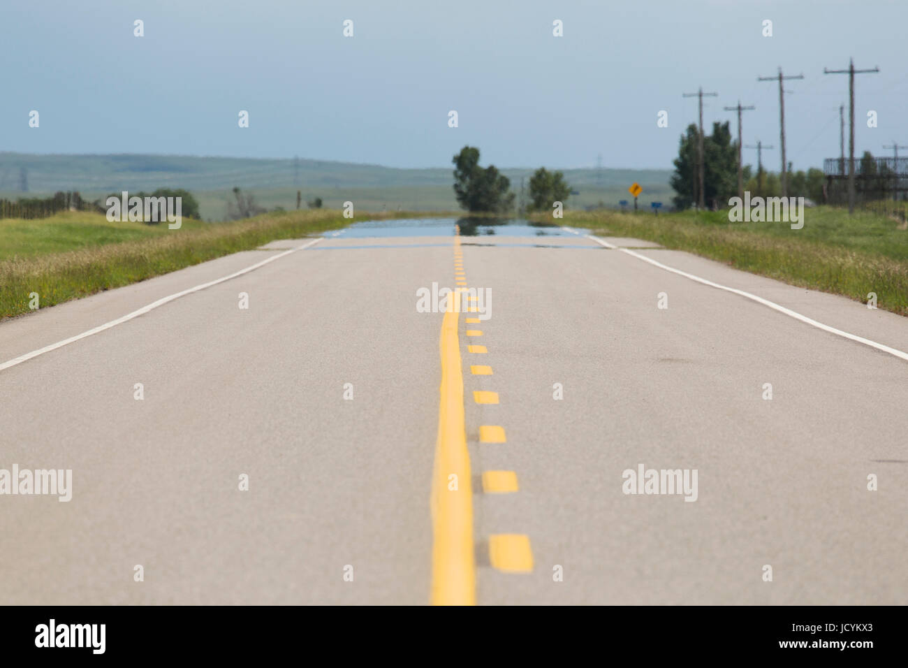 Leere Straße in Alberta, Kanada. Der Asphalt auf der Autobahn hat gelben Fahrbahnmarkierungen. Stockfoto
