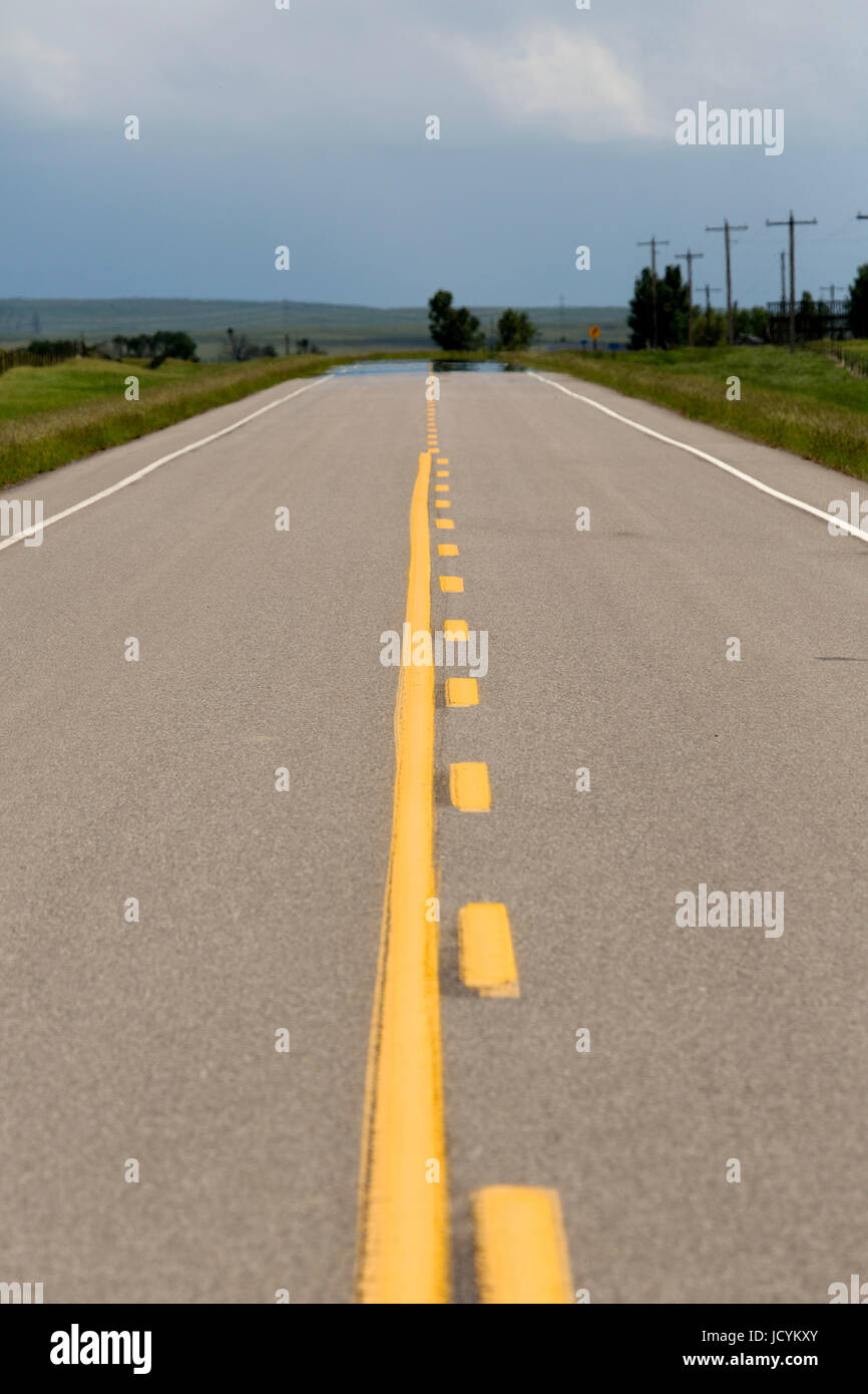 Leere Straße in Alberta, Kanada. Der Asphalt auf der Autobahn hat gelben Fahrbahnmarkierungen. Stockfoto