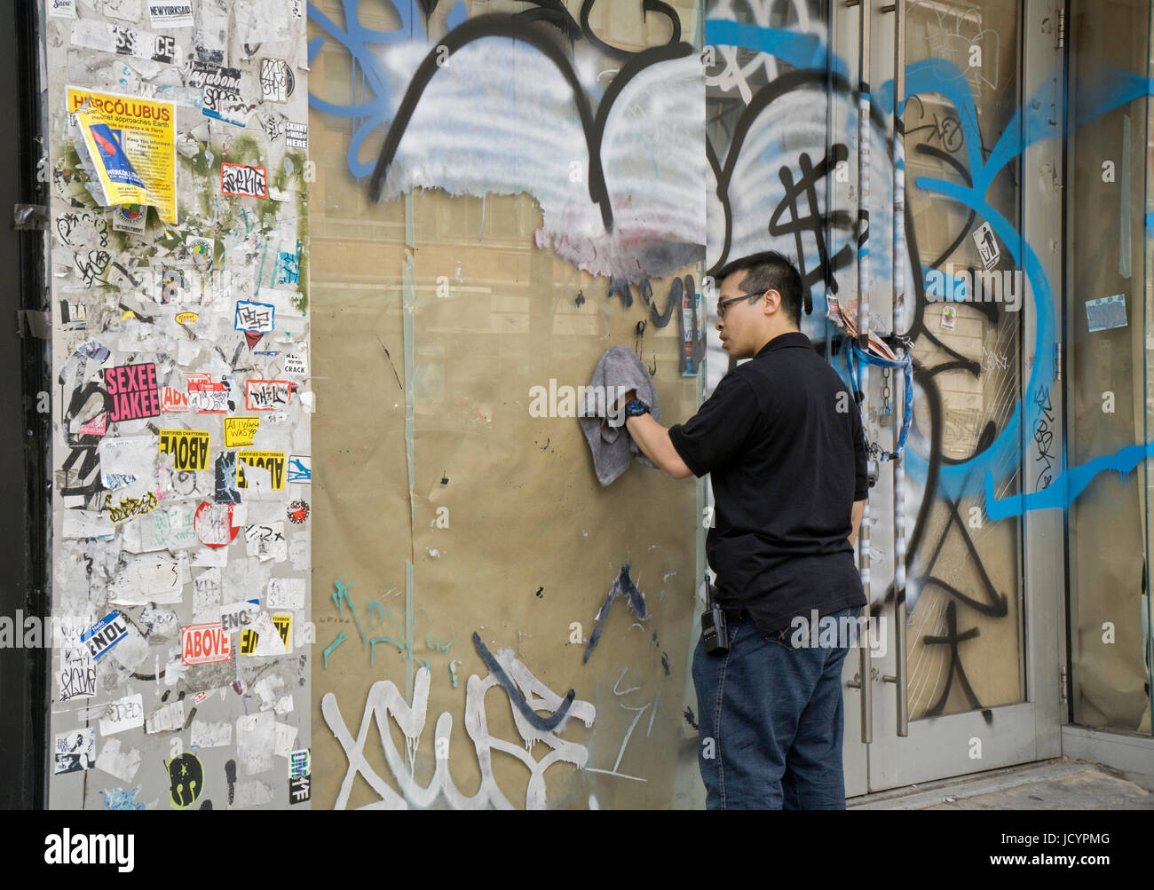 Ein junger Mann in Asian American Graffiti aus einer Wand und Fenster auf der West 14th Street in Manhattan, New York Unterstadt Reinigung. Stockfoto