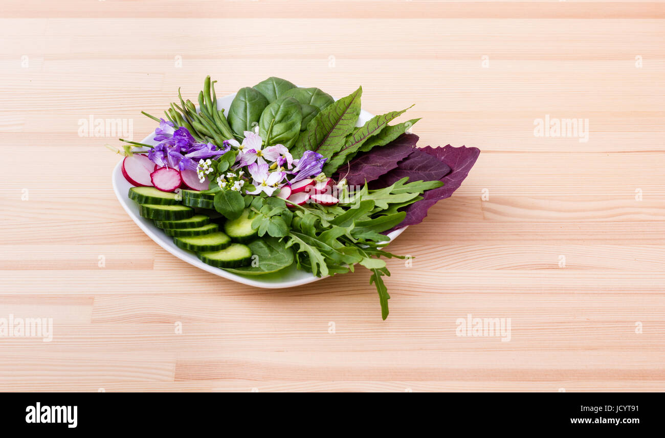 Salat mit verschiedenen Blättern, Gemüse und Blumen Stockfoto