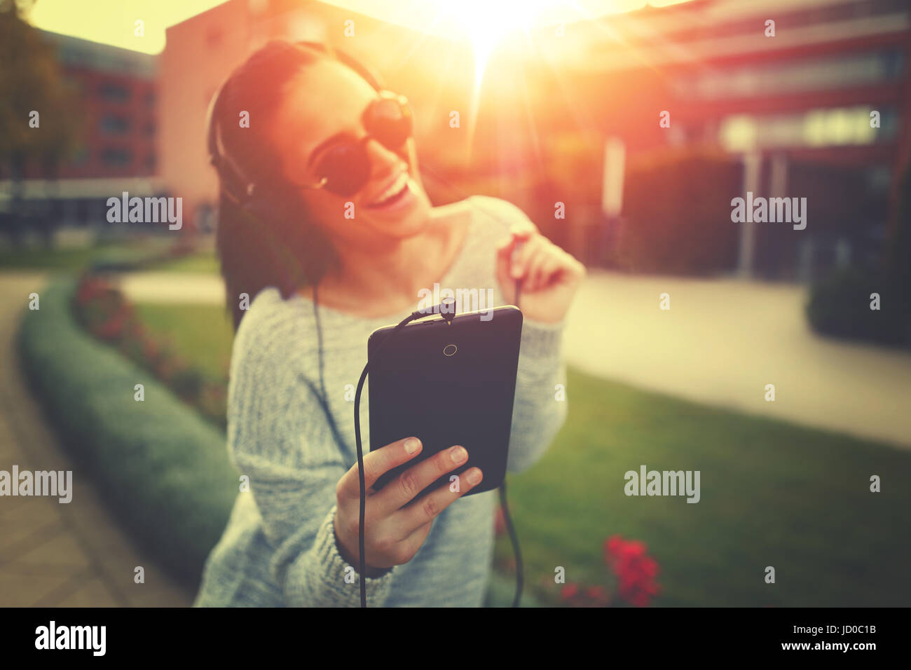 Junge Frau Musik hören von Tablet und Kopfhörer im Sonnenuntergang im freien Stockfoto