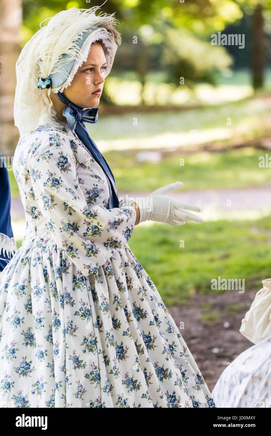 Hübsche junge Teenager, 14-15, Frau im Park gekleidet in viktorianischen Kostüm. Weißes Kleid mit blauen Blüten und Lacy hut mit Big Blue Ribbon gebunden. Von der Seite. Stockfoto