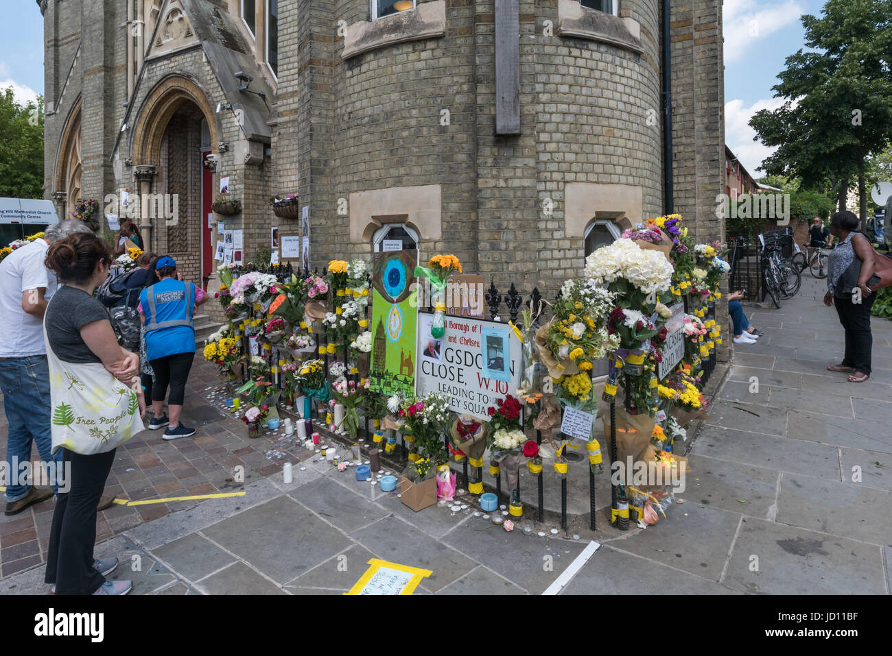 17. Juni 2017 - London, UK - London, UK. 17. Juni 2017. Plakate an Laternenmasten, Wänden und Tafeln zeigen die ergreifende Bilder derjenigen, die das verheerende Feuer in das Hochhaus mit brennbarem Material verkleidet, und hatte keine funktionierende Brandmeldeanlage fehlt. Das ganze Gebiet rund um den Turm noch abgesperrt, aber die grausige geschwärzte Hulk Grenfell Turm dominiert. Außerhalb der methodistischen Kirche, die eine Fläche für Ehrungen, Kerzen und Blumen für die Toten und vermissten beiseite, jetzt tot, werden deren Zahl jetzt gedacht, um über 150 sein. Peter Marshall ImagesLive (C Stockfoto