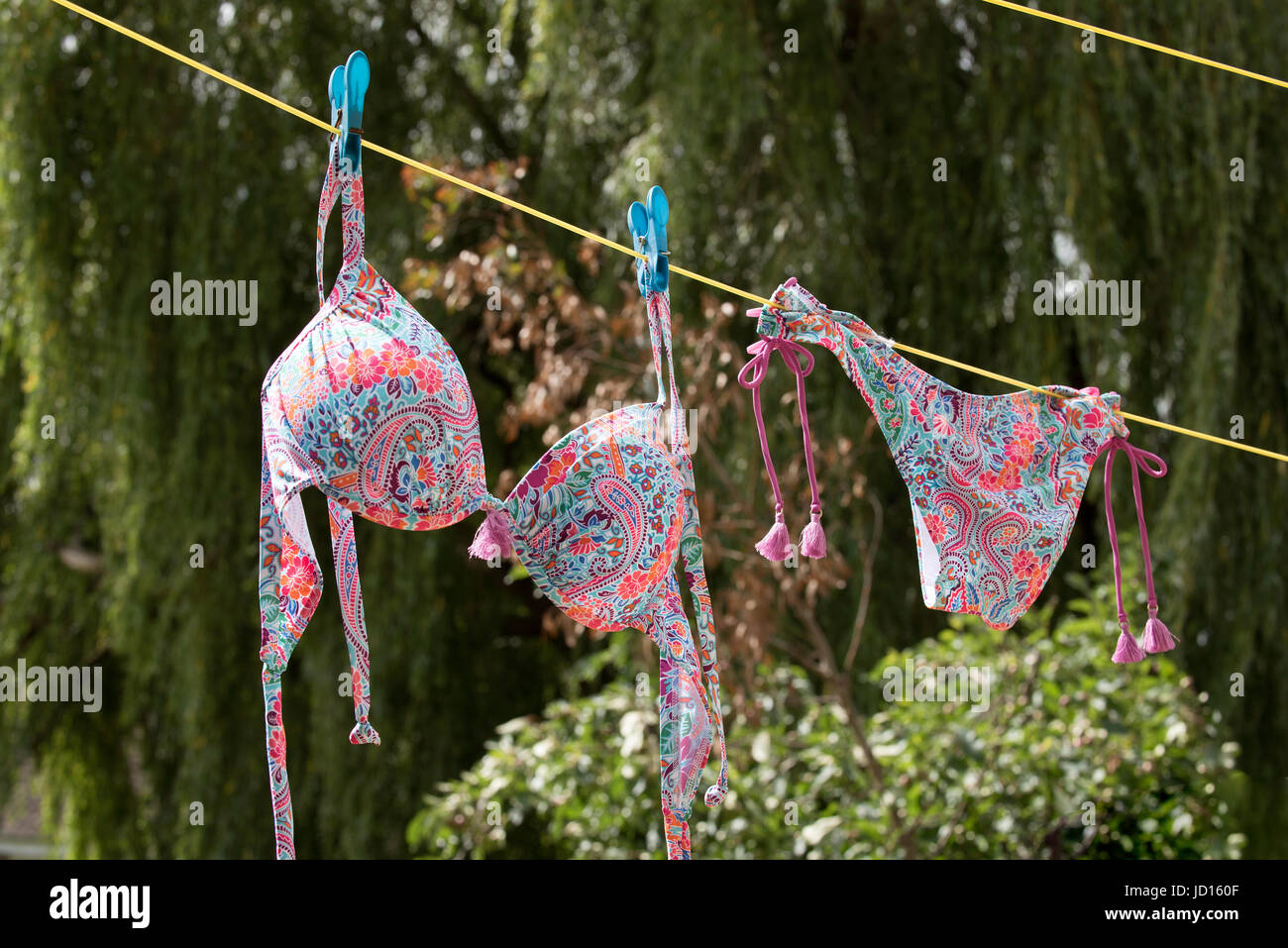 Einen bunten Bikini an eine Wäscheleine hängen Stockfoto