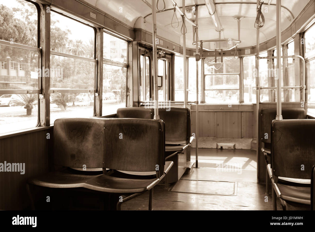 Innenraum einer alten Vintage Straßenbahn. Innen ist leer, hölzernen Sitze. Schatten. Durch die Fenster sehen Sie Bäume. Sepia. Melancholischen Hintergrund Stockfoto