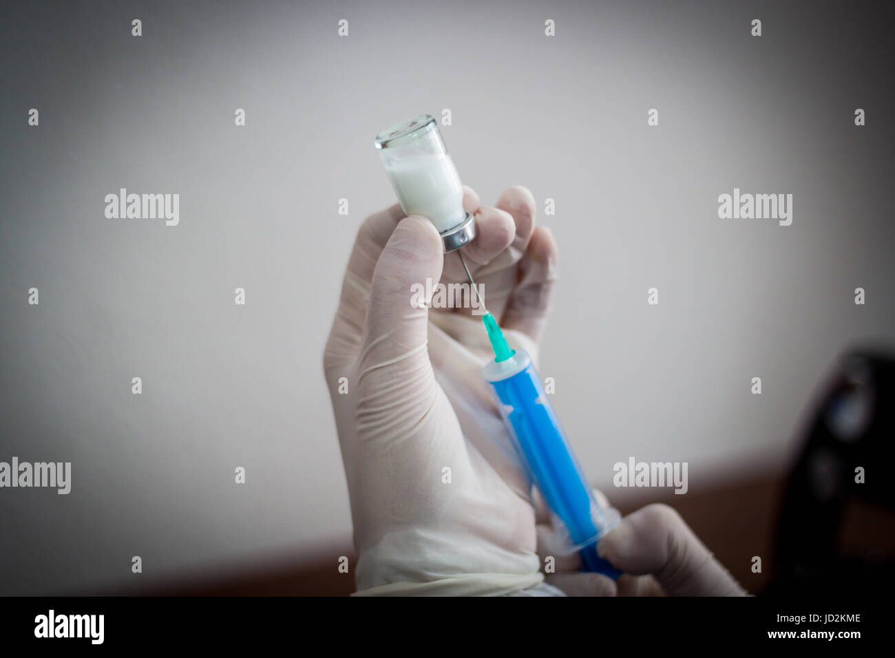 Junger Arzt bereitet eine Injektion zu einem Patienten, der injizierten Flüssigkeit in die Nadel halten sehr sorgfältig Stockfoto