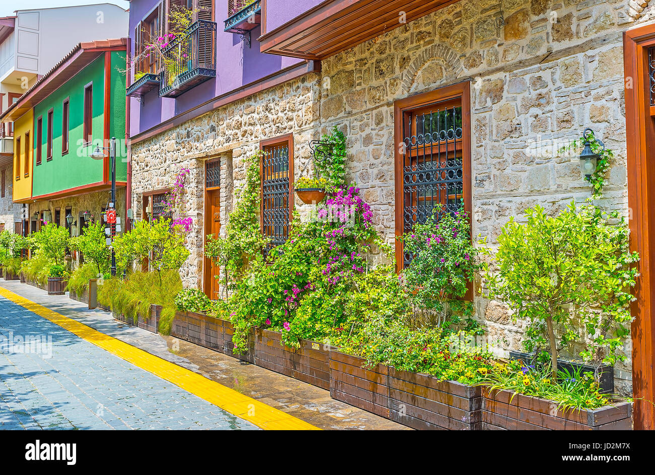 Die Holzbottiche mit Bäumen, Sträuchern und Blumen an den Wänden der alten Hütten sind die perfekte Straße Dekore, Kaleici, Antalya, Türkei. Stockfoto