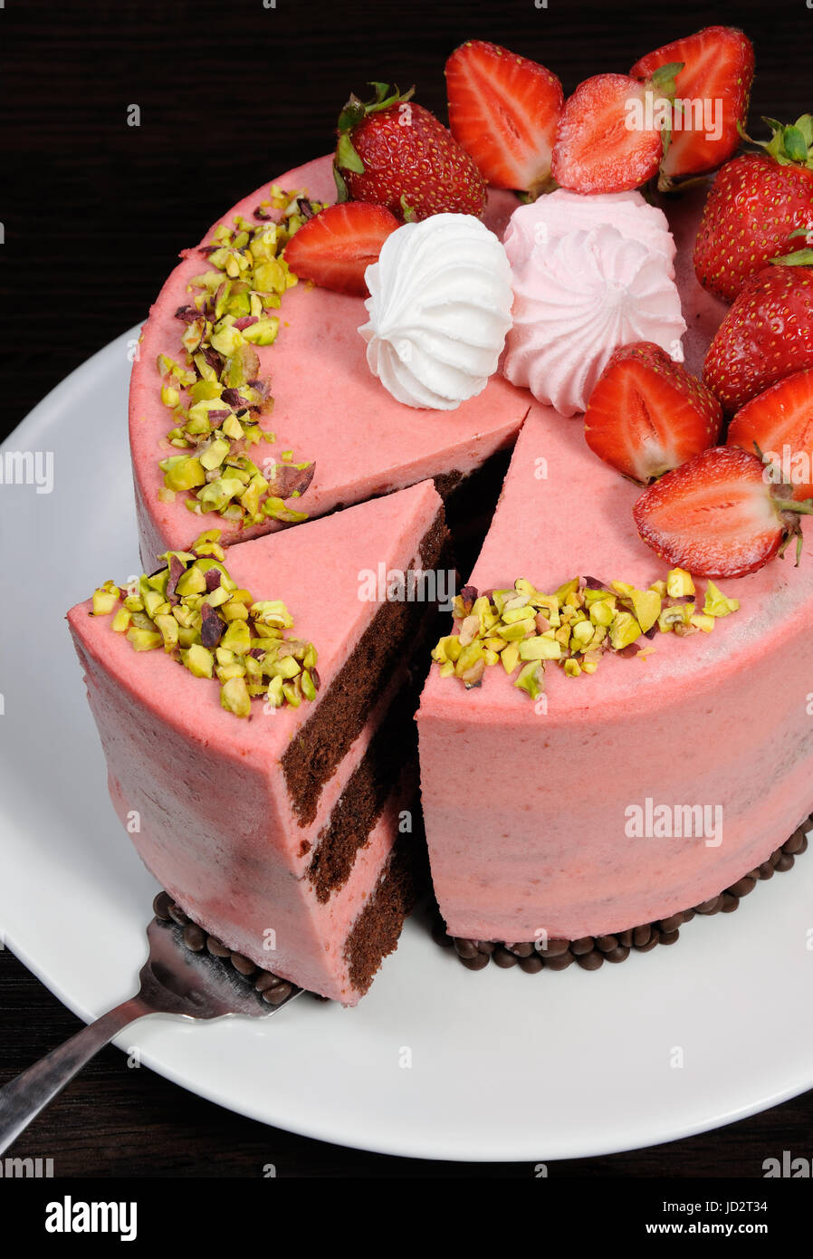 Ein Schnitt Stück Schokolade Erdbeer Mousse Torte mit Beeren, Baiser und Pistazien dekoriert Stockfoto