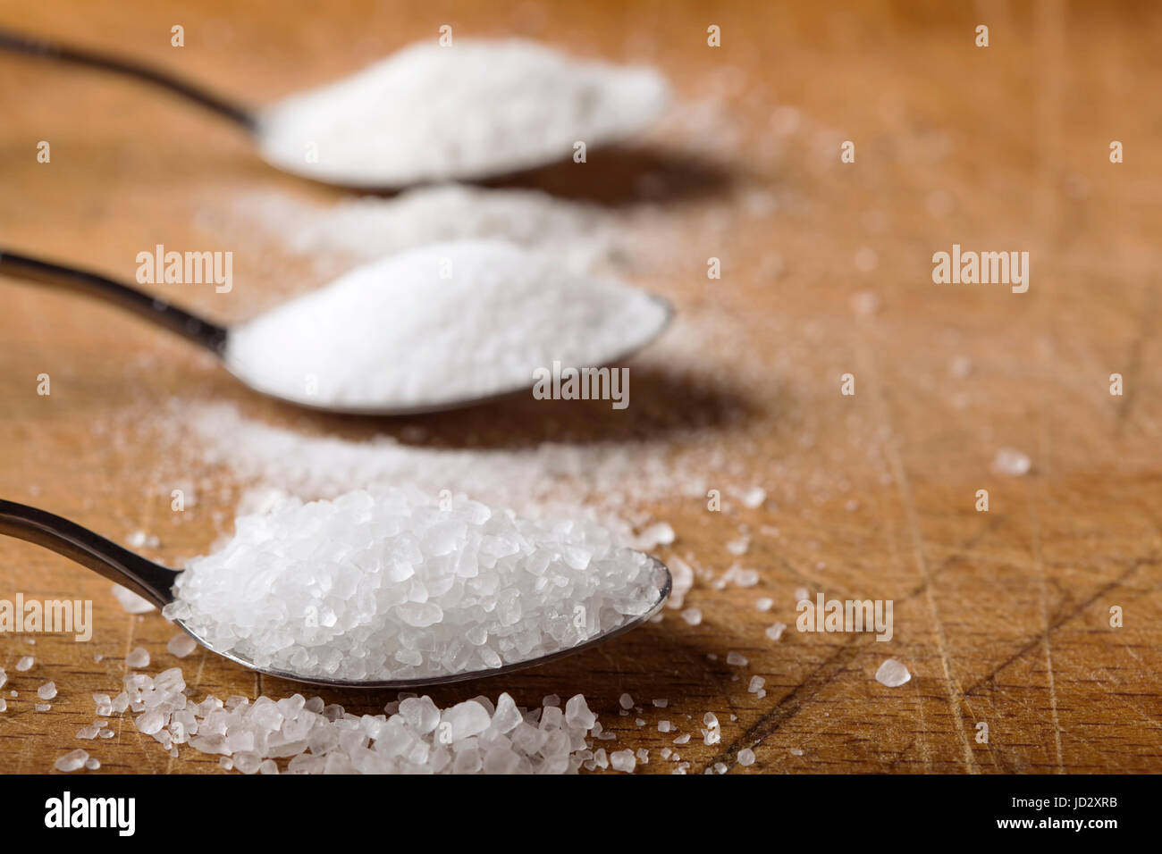 Nahaufnahme von Löffel gefüllt mit Salz über hölzerne Hintergrund Stockfoto