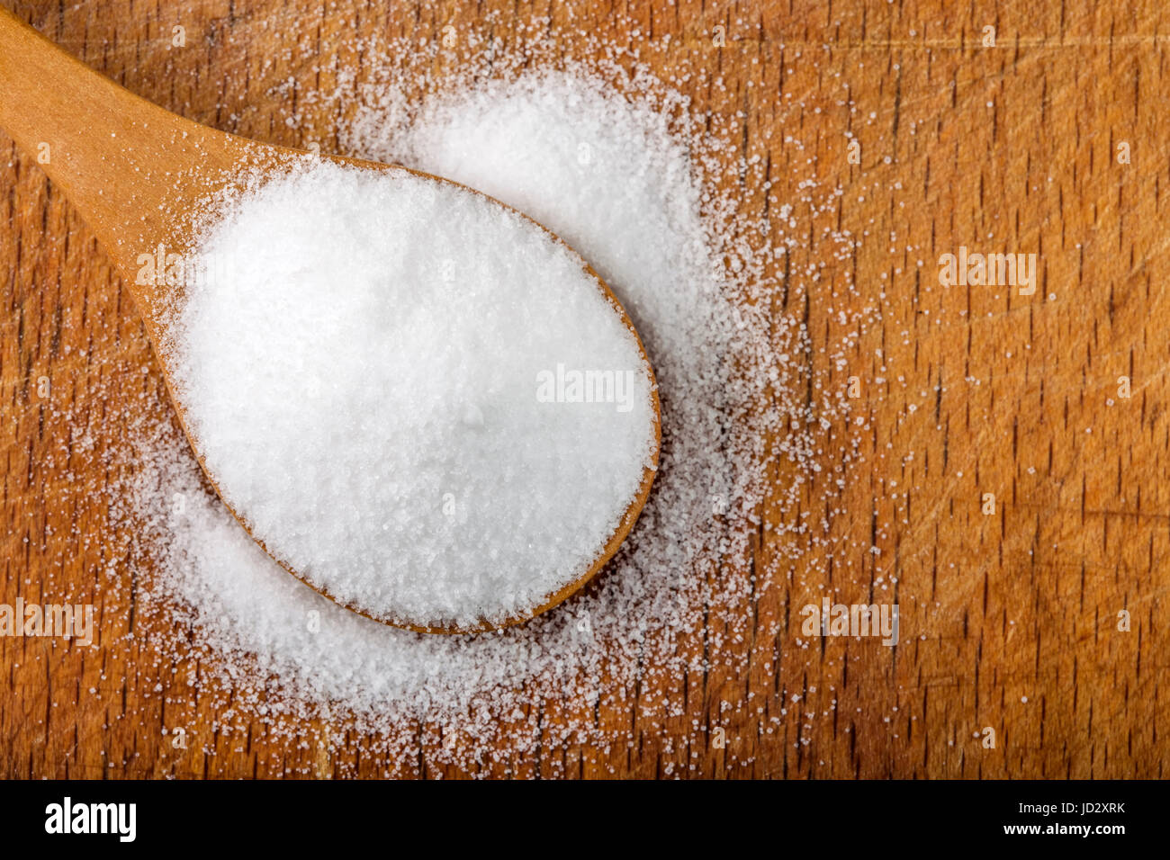 Holzlöffel gefüllt mit feinem Salz über hölzerne Hintergrund Stockfoto