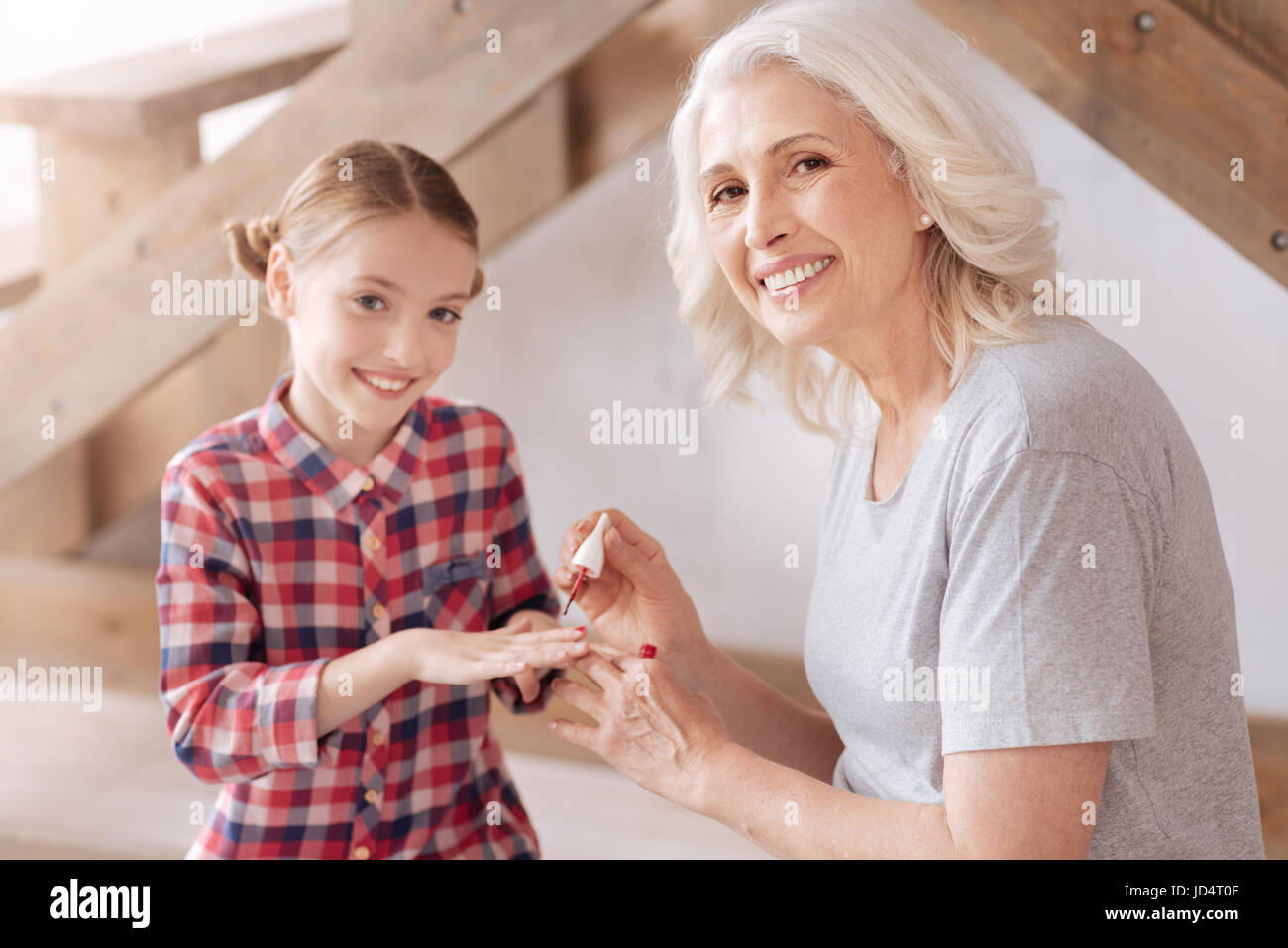 Freudige hübsche Frau, die Malerei ihre Enkelinnen Nägel Stockfoto