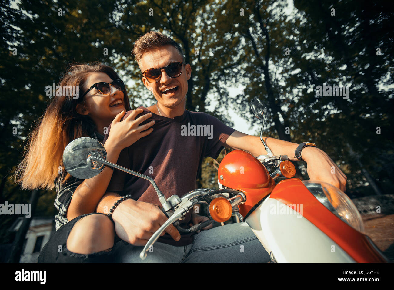 Junges attraktives paar Teenager trägt Sonnenbrille auf Retro-Motorrad im Park, Hipster-Konzept, 120FPS slowmotion Stockfoto