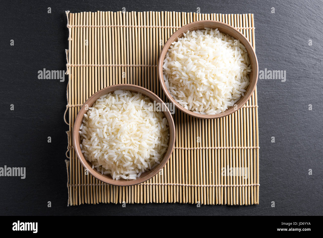 Ansicht von oben: gedämpfte gekochten Basmati-Reis in Runde Keramik Schalen über schwarzen Stein Stockfoto