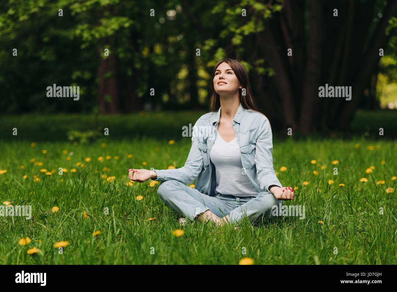 Schöne junge Mädchen in Freizeitkleidung meditieren im Frühlingspark Stockfoto