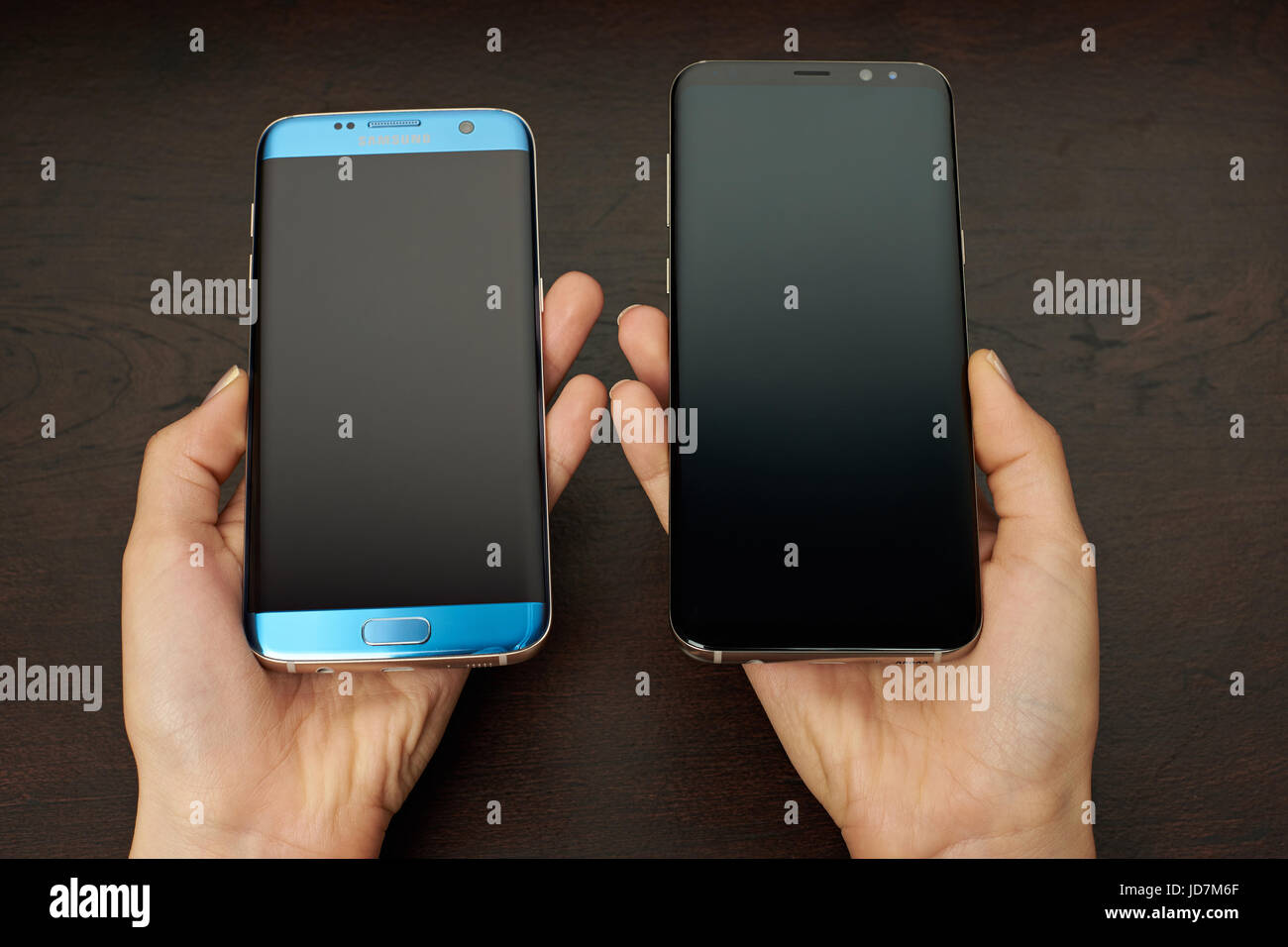 New York, USA - 13 Juni plus 2017:Samsung s8 und s7 Rand Smartphone in den Händen auf dunklem Holz Stockfoto