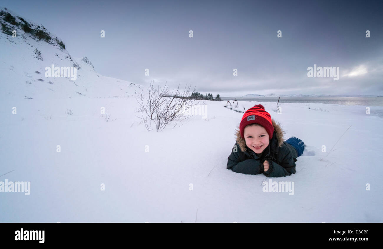 Junge liegend im Schnee bedeckt Landschaft, lächelnd, Island, Europa. Island-Natur 2017 Winterkälte Stockfoto
