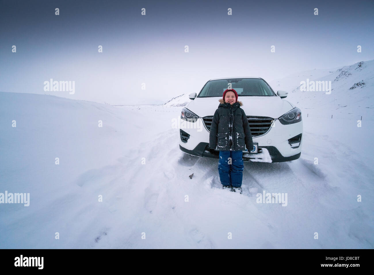 Junge vor stationären Auto auf verschneite Landschaft, Island, Europa steht. Island-Natur 2017 Winterkälte Stockfoto