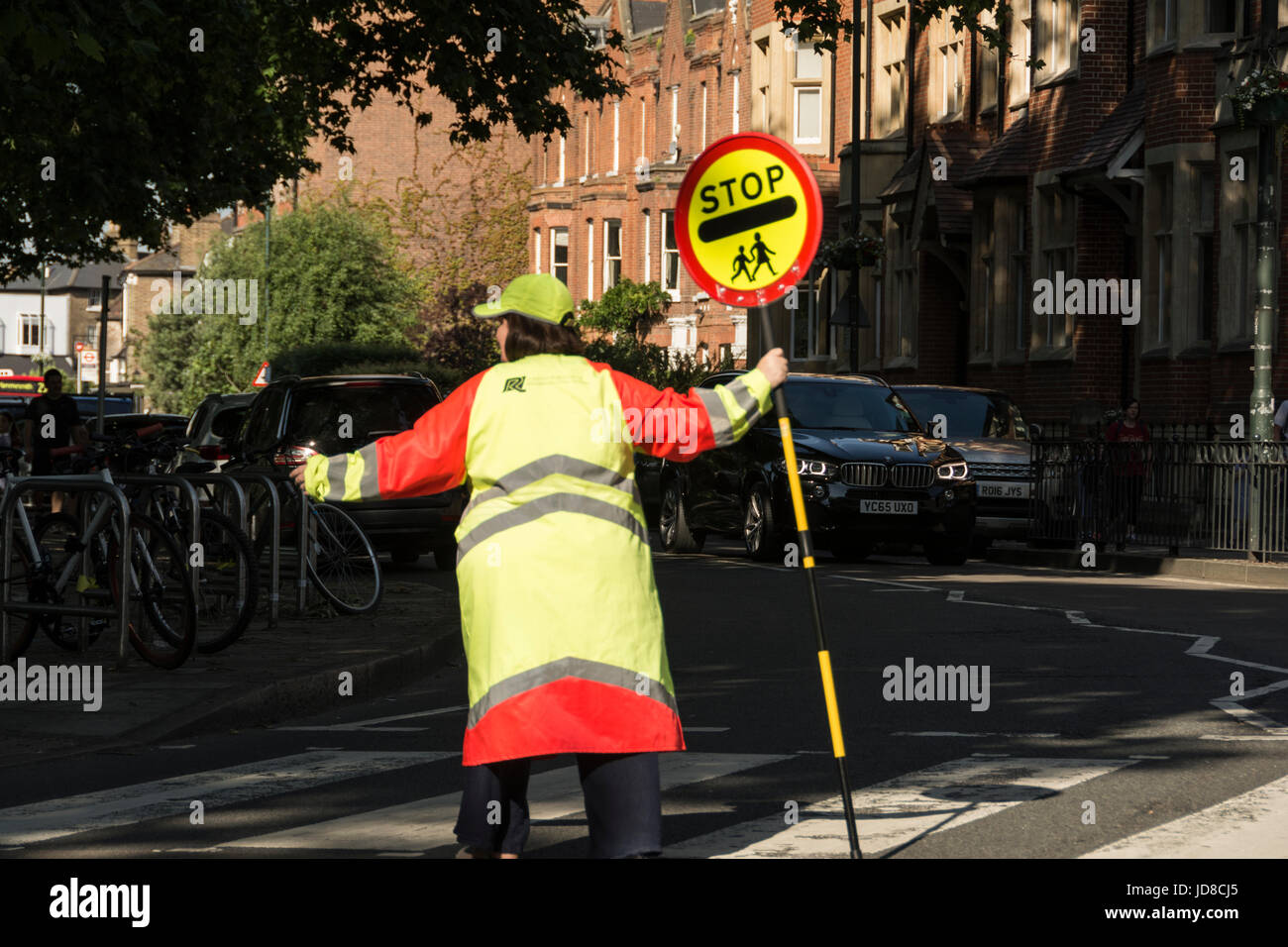Eine Lutscher-Dame, die den Verkehr auf einer Zebrakreuzung vor der St Osmond's School, Church Road, Barnes, London, SW13, unterblieg, England, Großbritannien Stockfoto