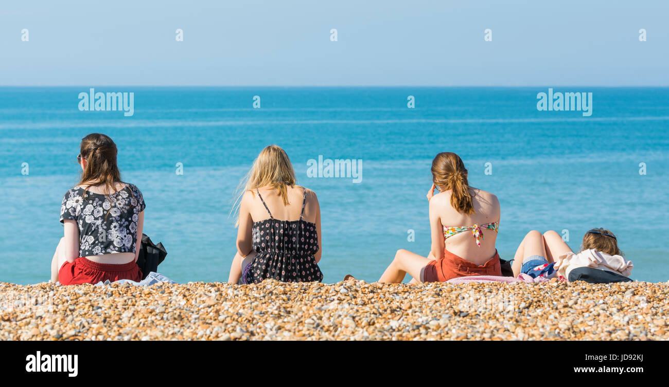Freundinnen sitzen auf einem Kiesstrand an einem heißen Tag im Sommer in Großbritannien. Stockfoto