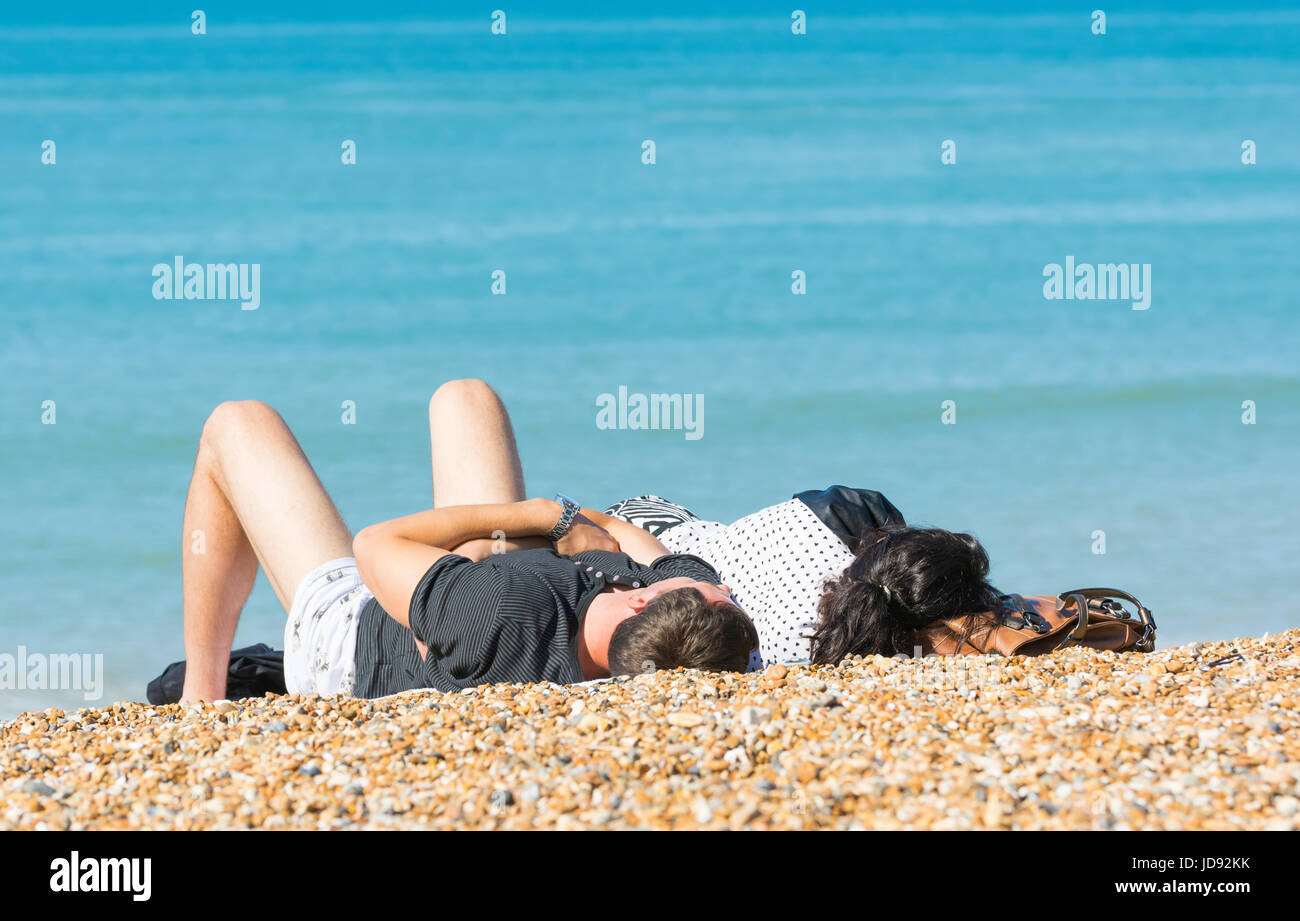 Paar im Sommer in der Sonne auf einem Kiesstrand verlegen. Stockfoto