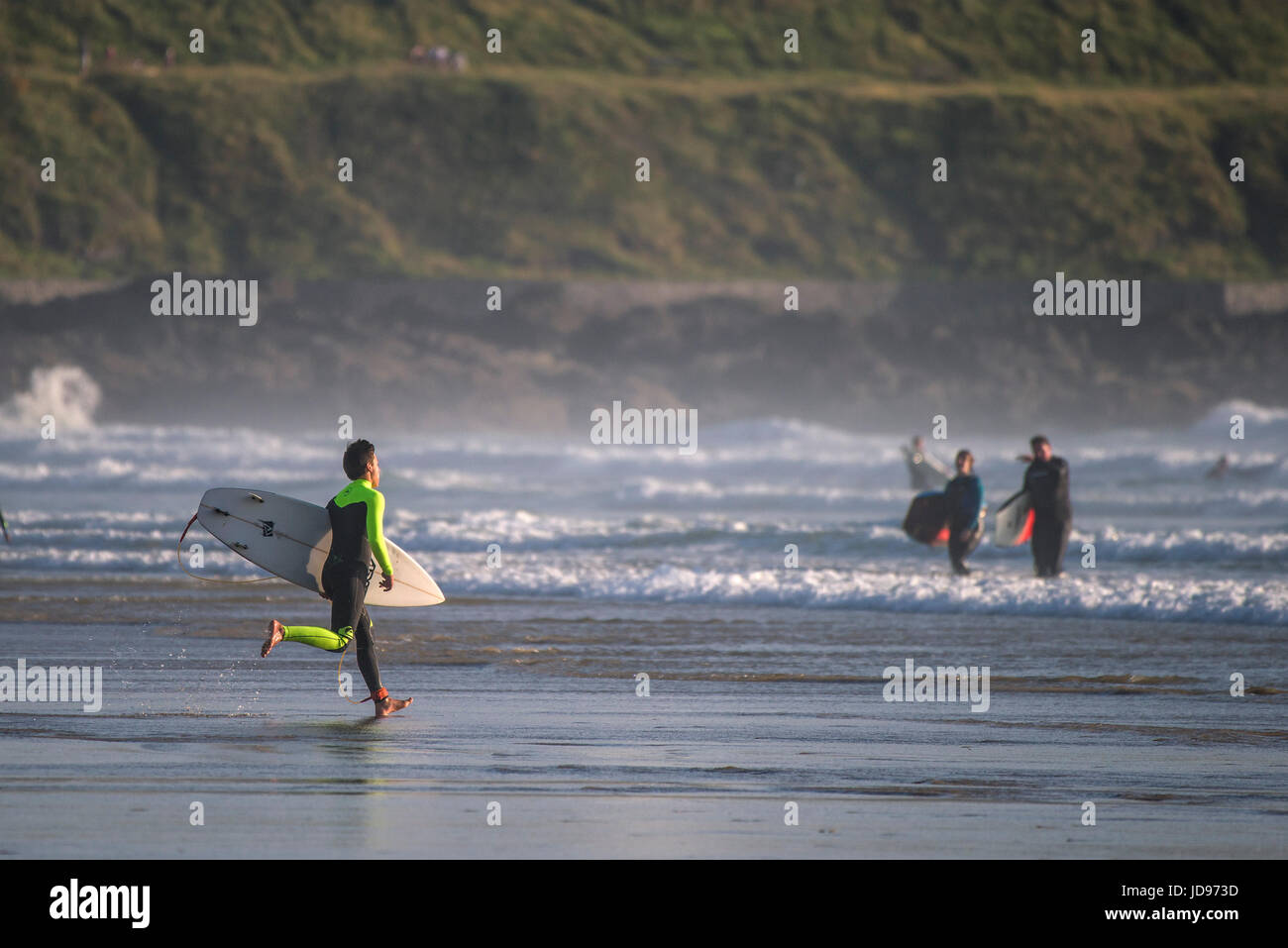 Ein Surfer am Fistral Beach in Newquay, Cornwall ins Meer laufen. Stockfoto