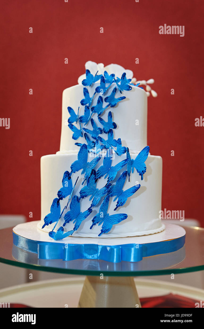 Zweiklassen Hochzeitstorte mit blauen Schmetterlingen auf Gläser Tisch. Stockfoto