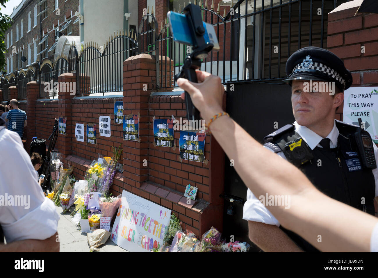 Nach dem Angriff auf eine Gruppe von muslimischen Männern draußen der Finsbury Park-Moschee die eine Person getötet und ernsthaft verletzt andere zehn, traf Polizisten Wache der islamischen Gebäude wo Blumen, am 19. Juni 2017, im Stadtteil Islington, North London, England geblieben sind. Stockfoto