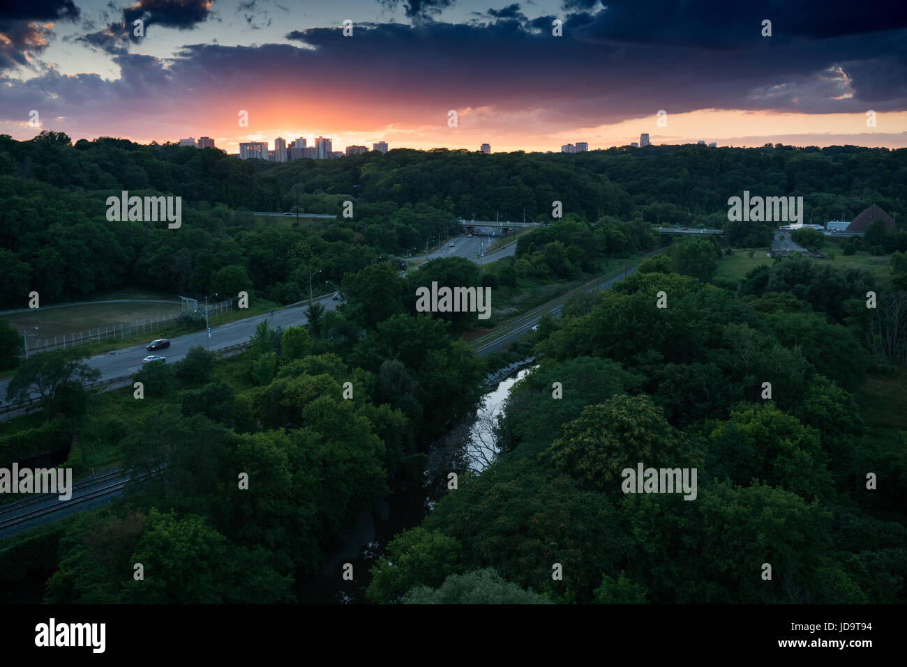 Skyline bei Sonnenuntergang im Hintergrund, Straßen durch Bäume im Vordergrund, Ontario, Kanada Stockfoto