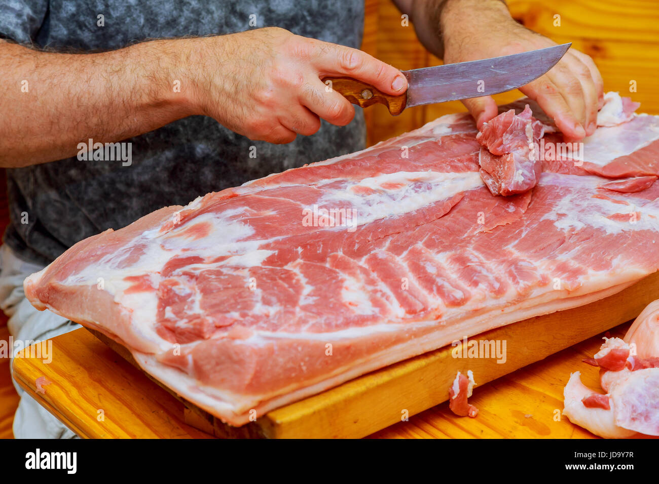 Mann schneidet frisches Stück Fleisch auf einem Holzbrett in die Küche zu Hause Stockfoto