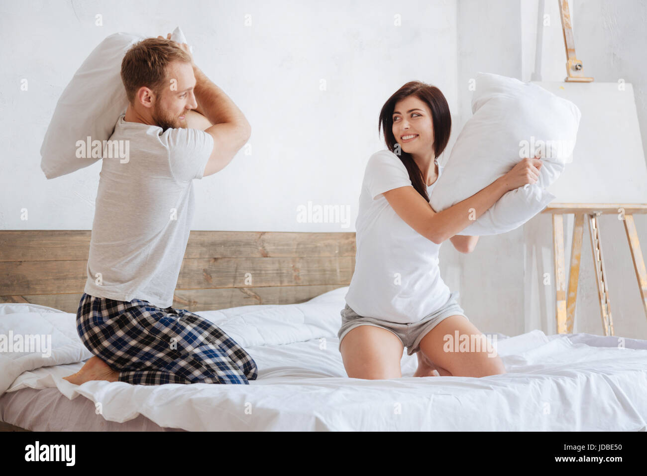 Aufgeregt tausendjährigen Freund und Freundin werfen Kissen Stockfoto