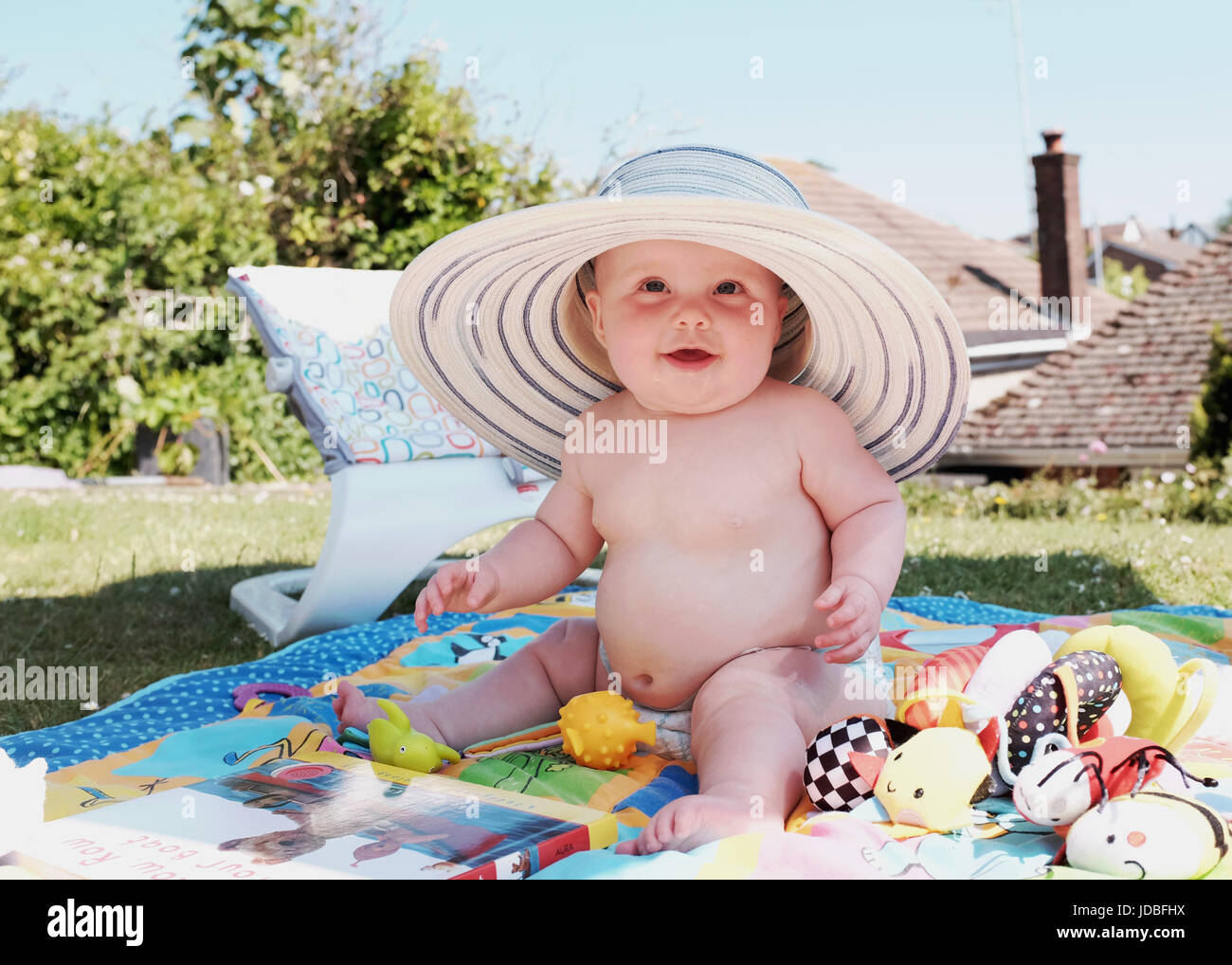 Niedliche 6 Monate altes Baby Mädchen Hut eine Erwachsene weibliche Sonne im Garten Foto von Simon Dack Stockfoto