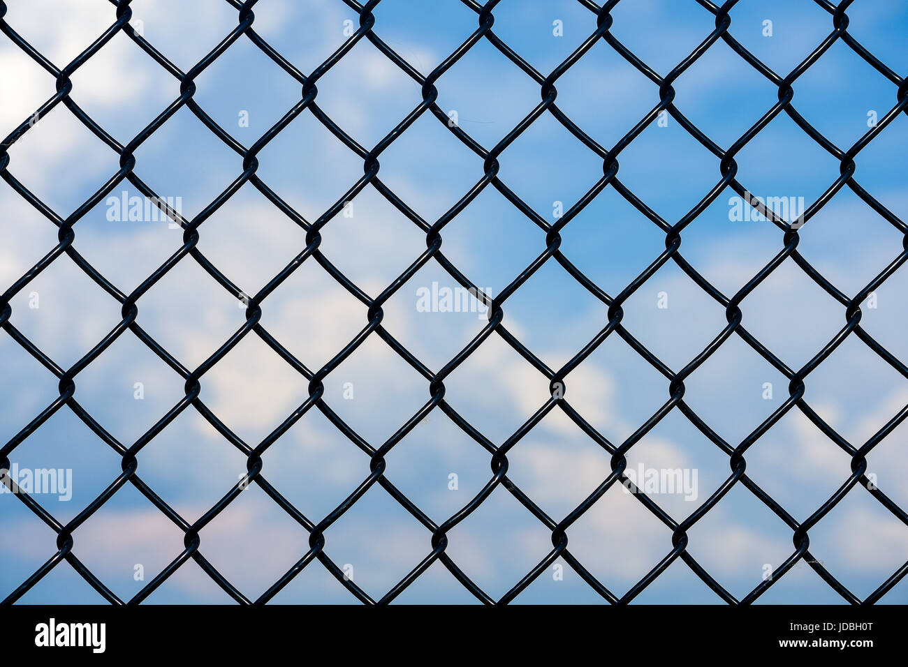 schwarzen Maschendrahtzaun mit blauem Himmel und Wolken-Hintergrund Stockfoto