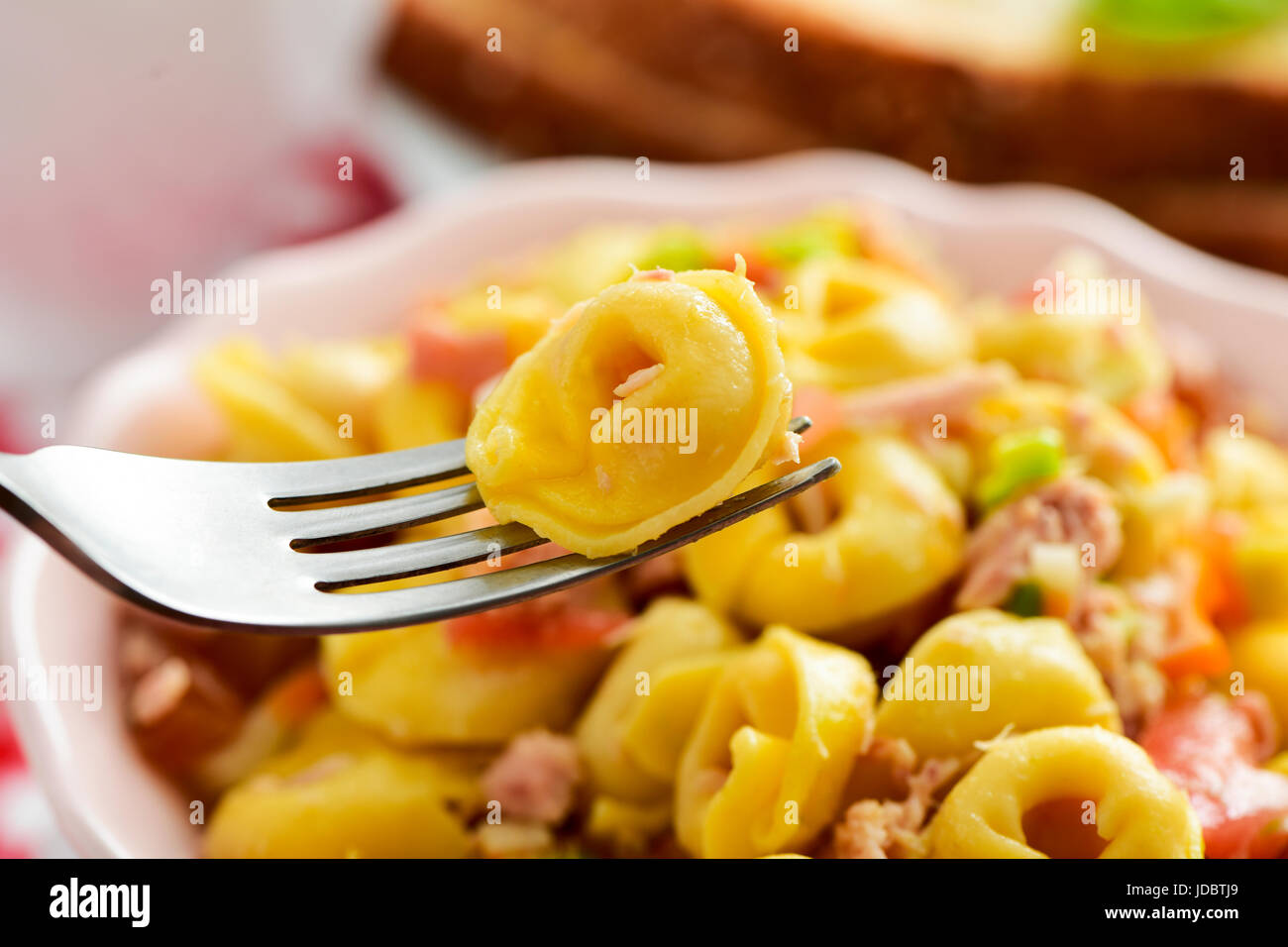 Nahaufnahme von einer Keramikschale mit einer Pasta Salat mit Tortellini auf einem Tisch zum Mittag- oder Abendessen Stockfoto