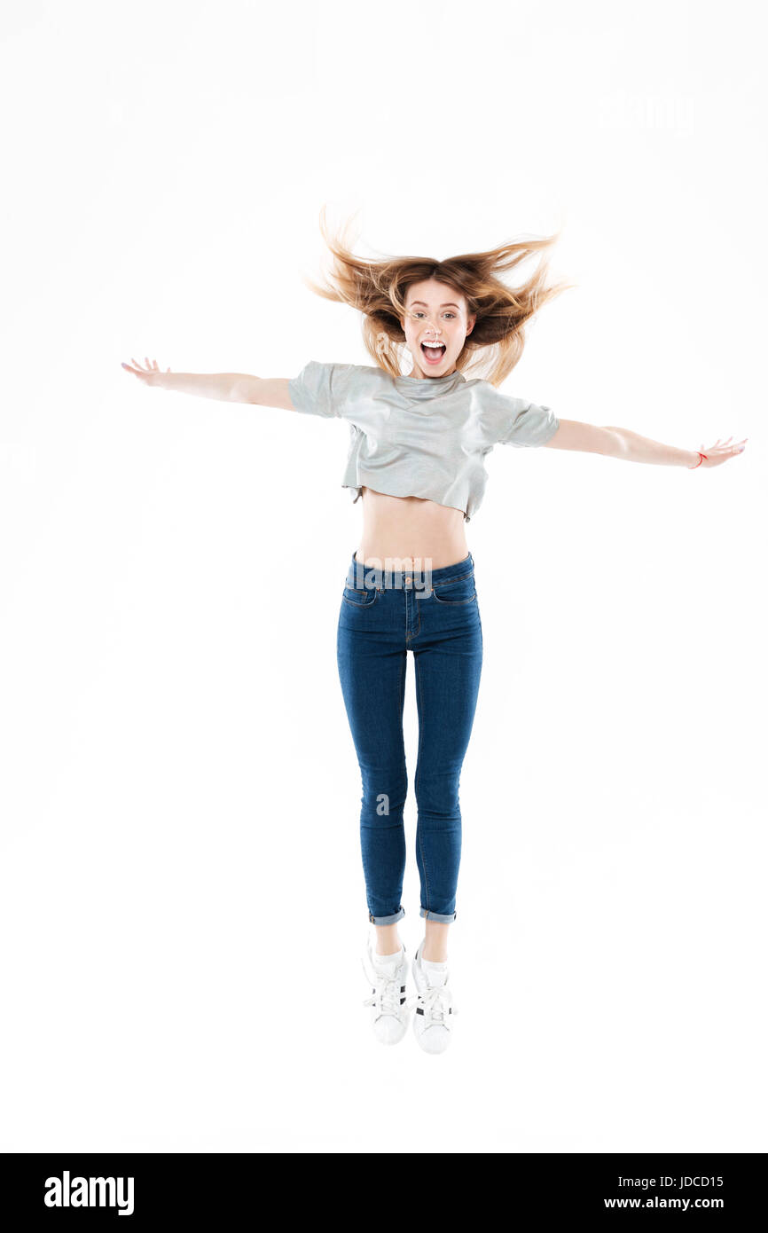 In voller Länge Portrait von ein fröhliches junges Mädchen springen mit ausgestreckten Händen isoliert auf weißem Hintergrund Stockfoto