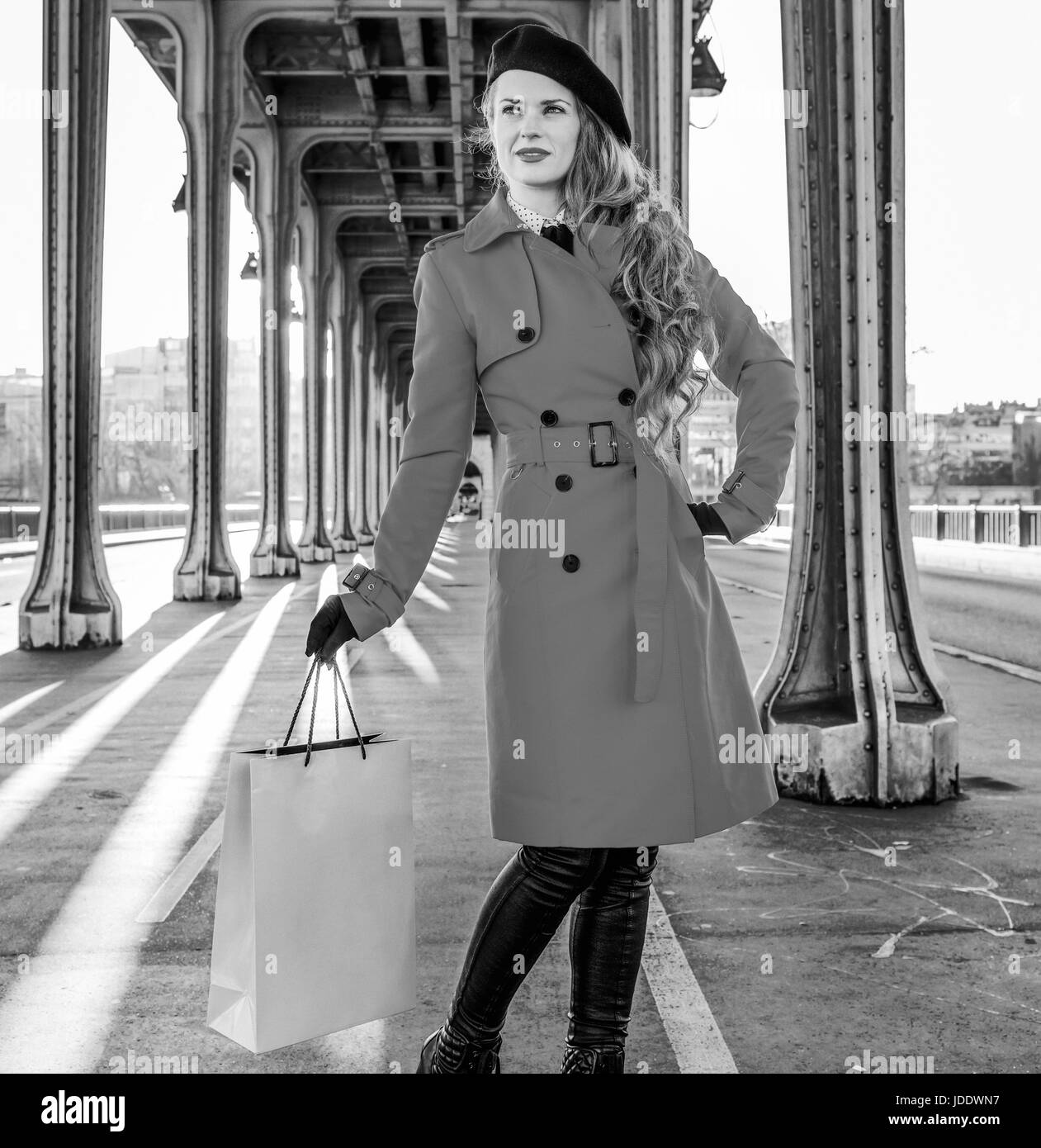 Hell in Paris. In voller Länge Portrait elegante touristische Frau im roten Mantel auf Pont de Bir-Hakeim-Brücke in Paris mit Einkaufstasche Stockfoto