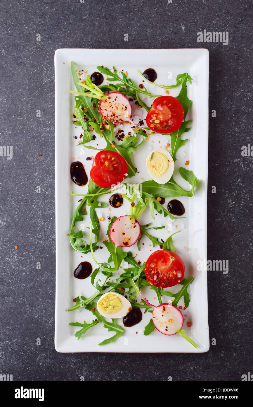 Frische Radieschen, Kirschtomaten, Wachtelei, Parmeggiano mit Balsamico-Glasur auf einem weißen Teller. Mediterranes Lebensgefühl. Gesunde Ernährung. Stockfoto