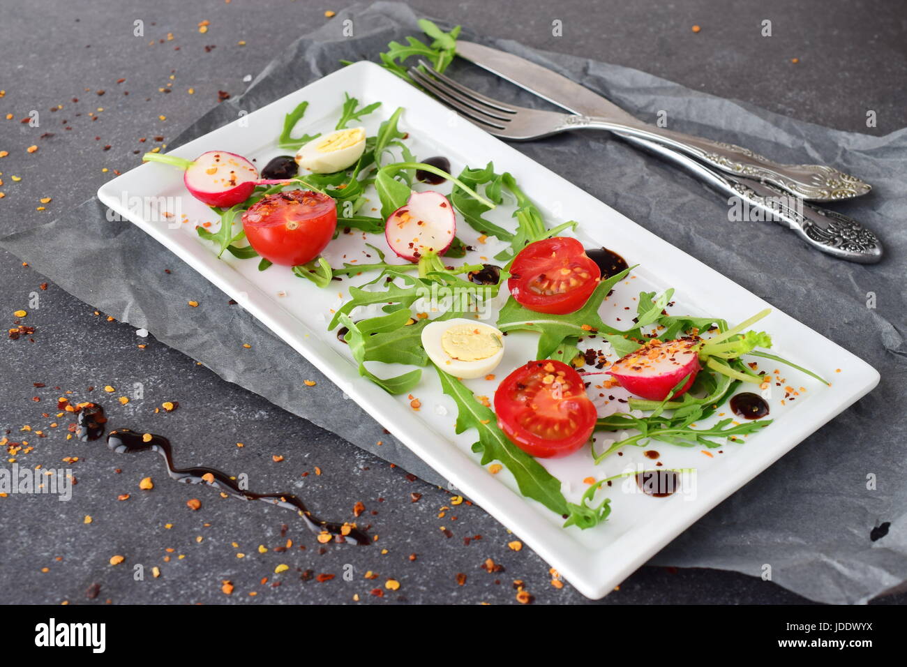 Frische Radieschen, Kirschtomaten, Wachtelei, Parmeggiano mit Balsamico-Glasur auf einem weißen Teller. Mediterranes Lebensgefühl. Gesunde Ernährung. Stockfoto