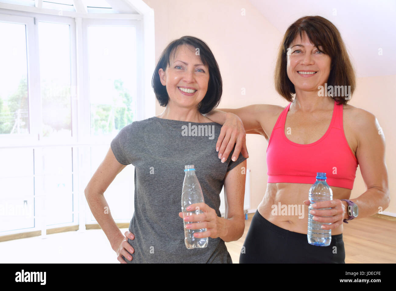 Porträt von Frauen im Alter mit Plastikflaschen, die Kamera und Lächeln zu betrachten. Gesunde Fitness-Konzept mit aktivem Lebensstil. Stockfoto