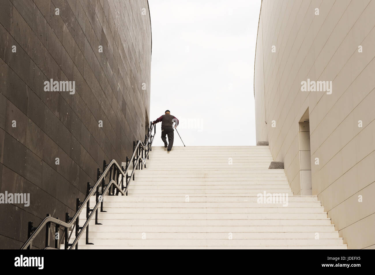 Alter Mann klettert die Treppe mit seinem Gehstock Stockfoto