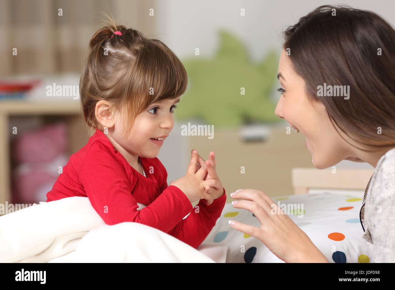 Mutter und Kleinkind tragen rote Hemd spielen zusammen auf einem Bett im Schlafzimmer zu Hause Stockfoto