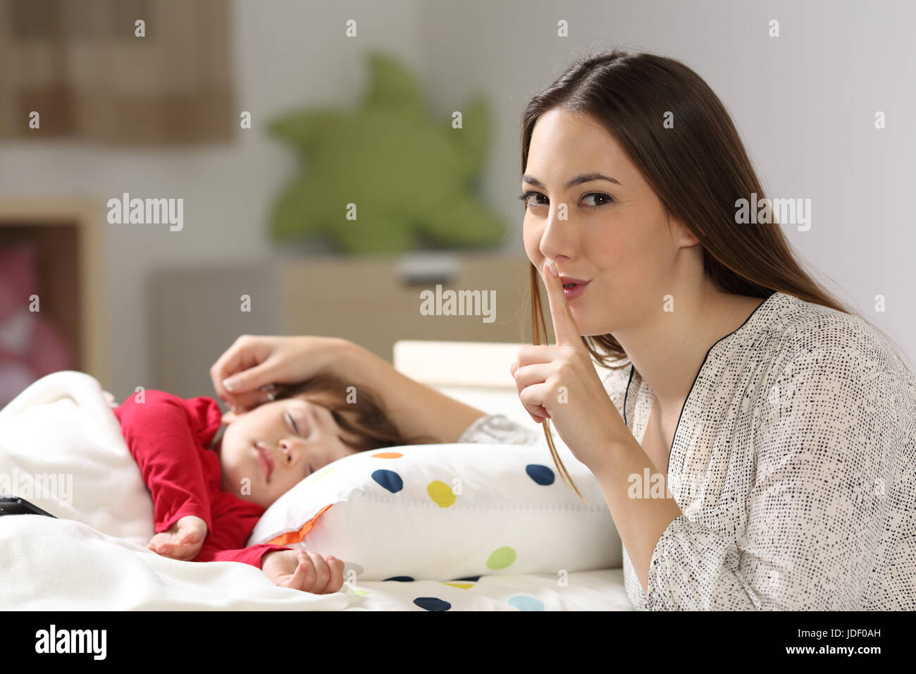 Mutter, bitte um Stille mit ihrem Kleinkind schlafen auf einem Bett im Schlafzimmer in einem Haus-Interieur Stockfoto