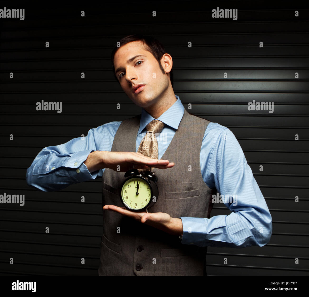 Gut gekleideter Mann hält eine Uhr. Stockfoto