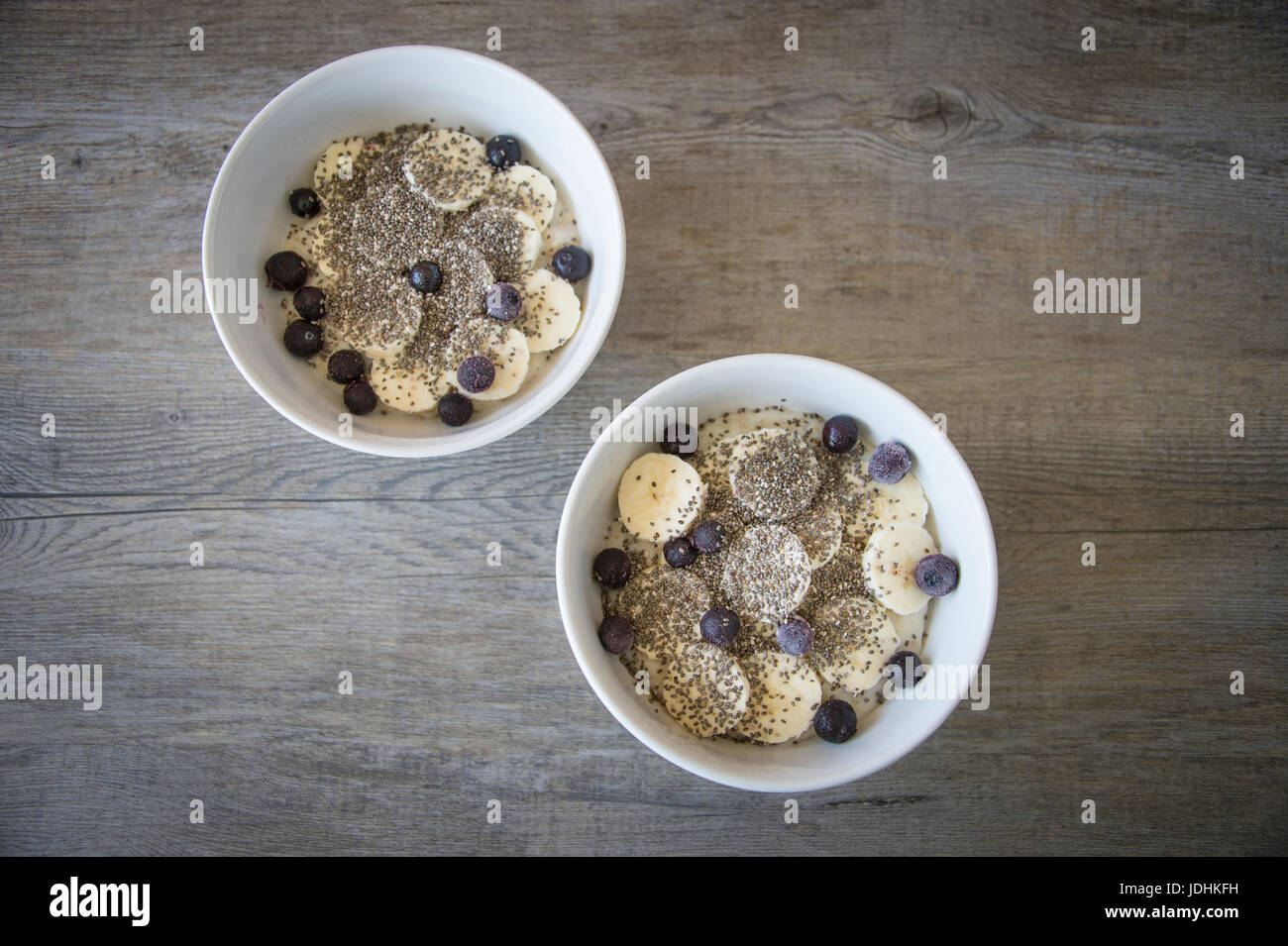 Zwei Schüsseln Porridge mit Banane, Chia-Samen und Heidelbeeren Stockfoto