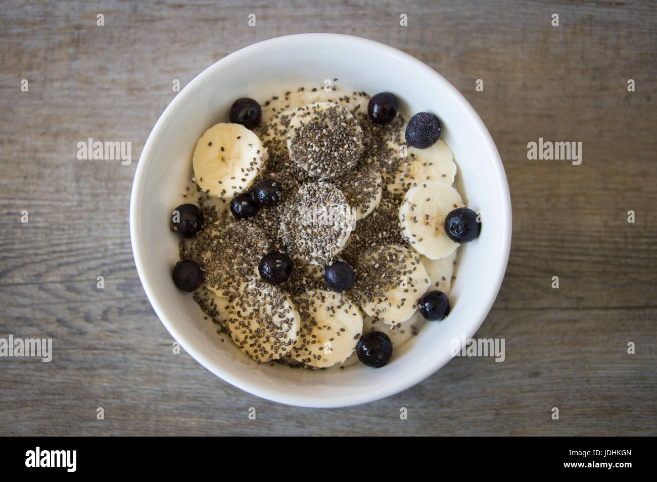 Schüssel Haferbrei mit Banane, Chia-Samen und Heidelbeeren, fotografiert von oben. Stockfoto