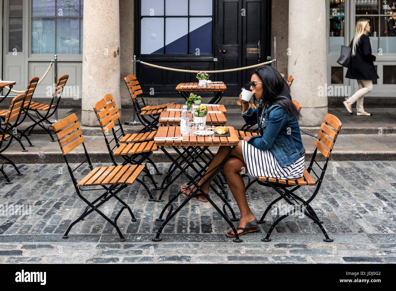 Eine junge schwarze Frau Kaffeetrinken am Bürgersteig Café, Covent Garden, London, UK Stockfoto